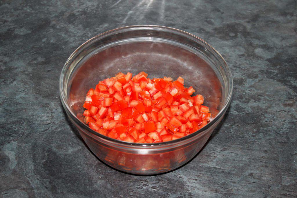 Deseeded chopped tomato in a glass bowl.
