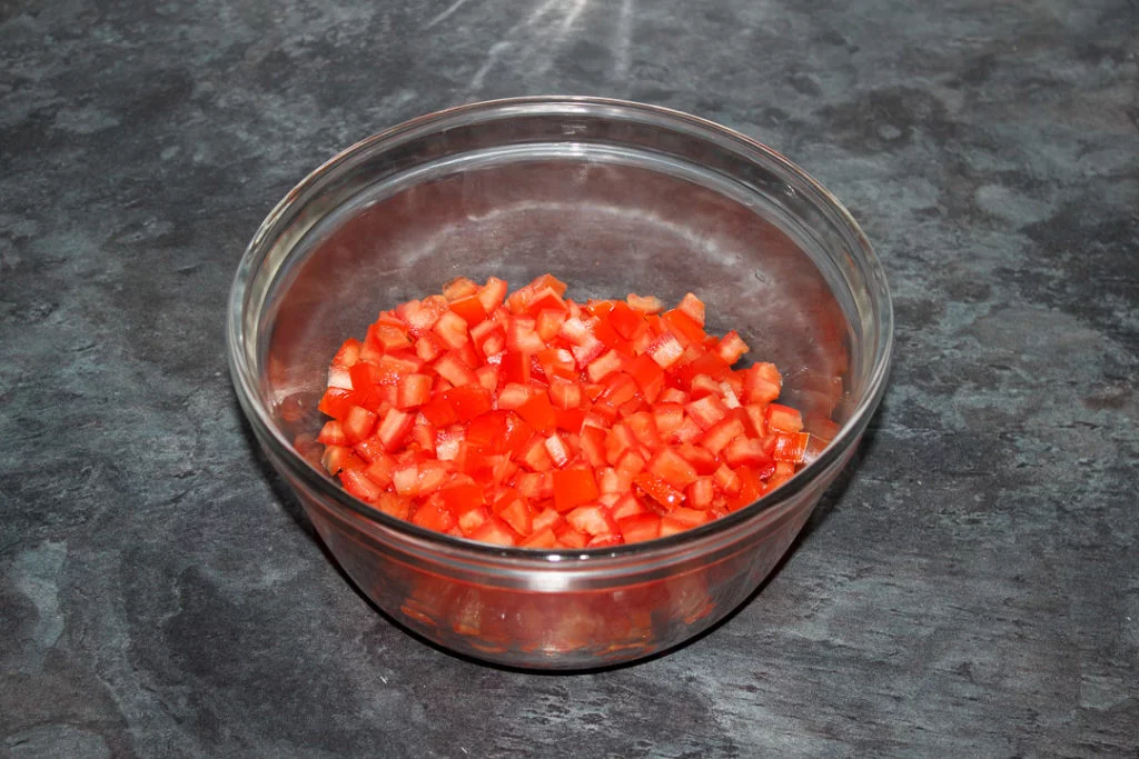 Deseeded chopped tomato in a glass bowl.
