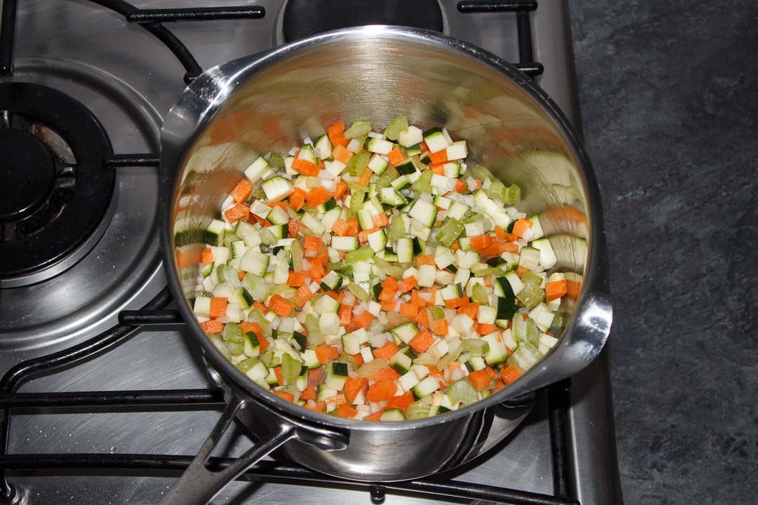 Carrot, courgette, celery and onion frying in a large saucepan