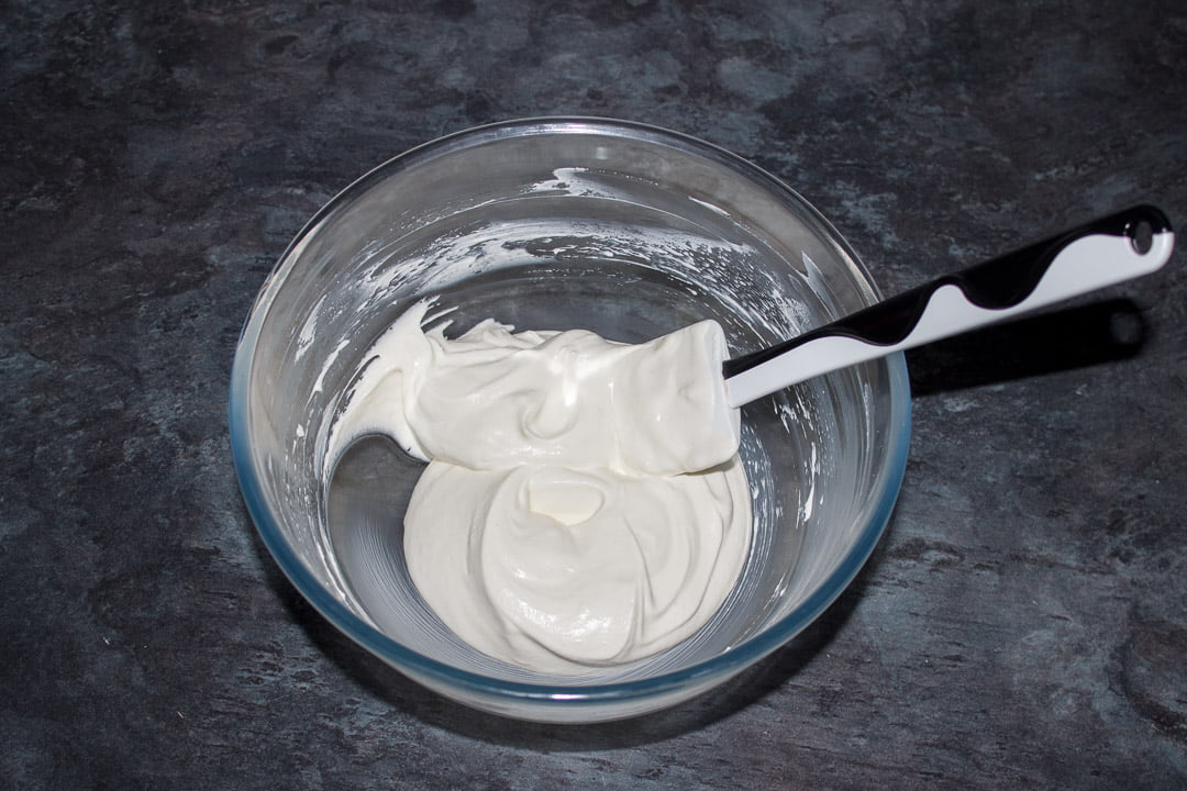 Cheesecake filling mixture in a glass bowl with a white spatula