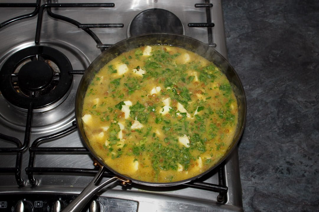 Fish curry in a pan with fresh coriander