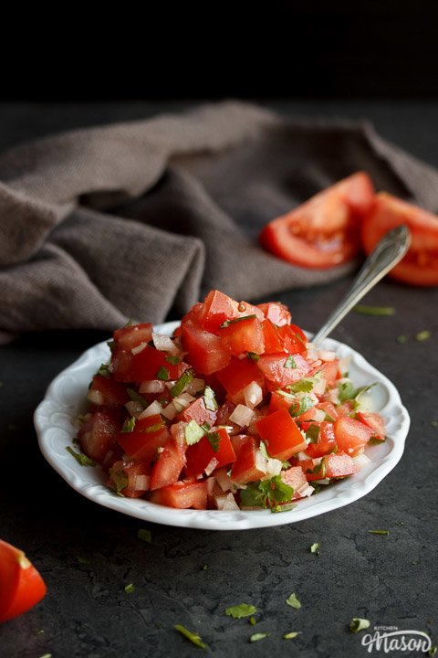 Fresh tomato salsa in a white bowl with a spoon