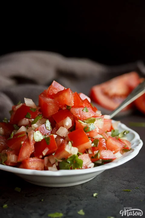 Fresh tomato salsa in a white bowl with a spoon