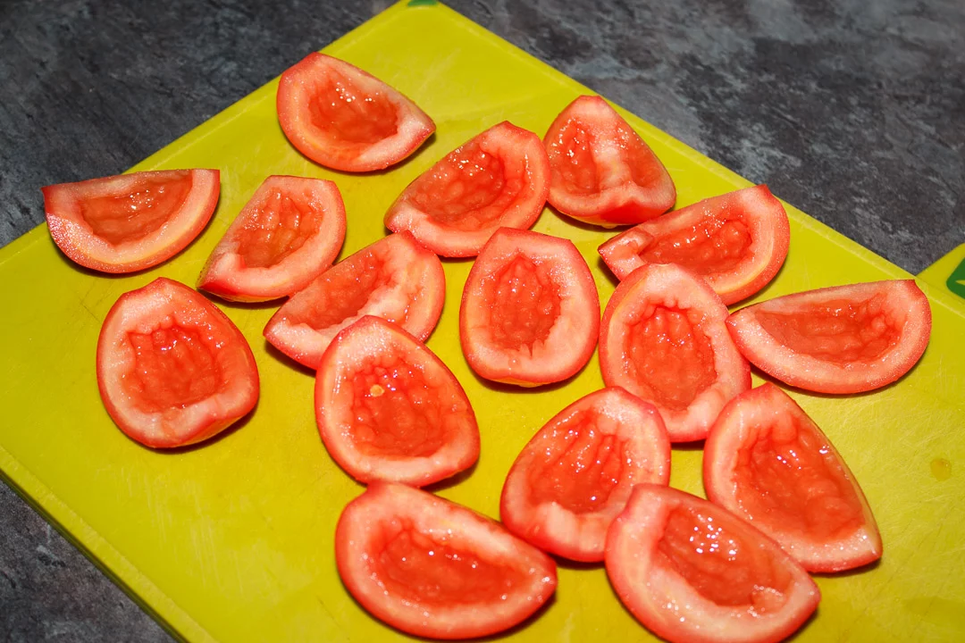 Quartered and desseded tomatoes on a green chopping board