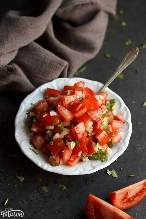Fresh tomato salsa in a white bowl with a spoon