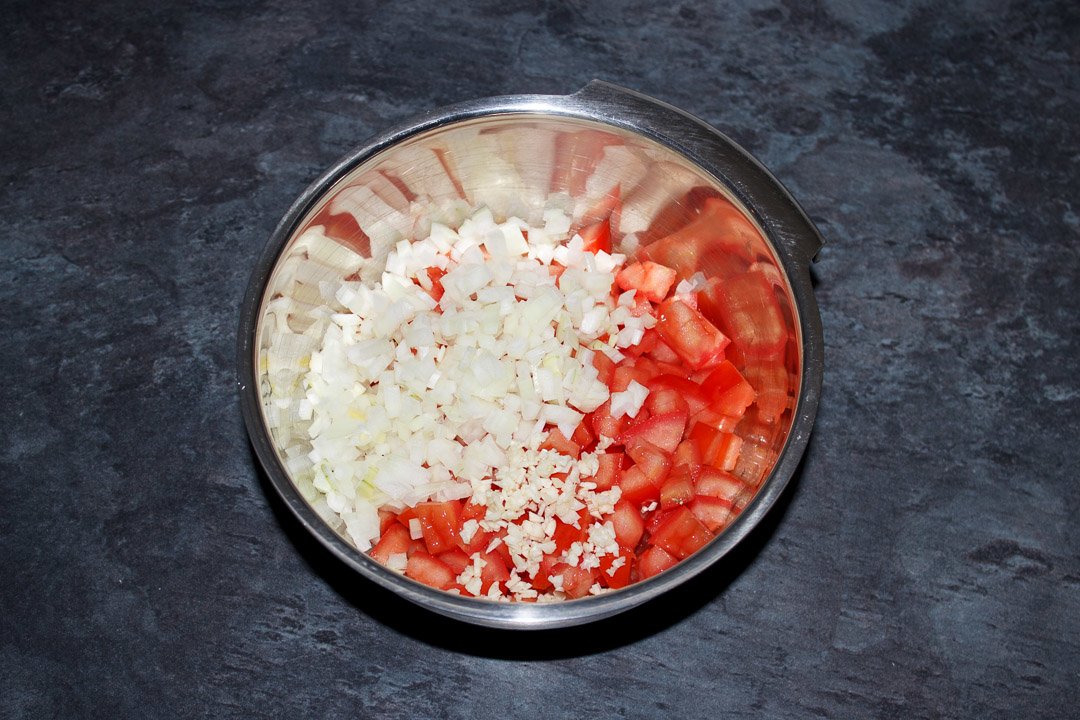 Diced desseded tomato, diced onion and garlic in a silver bowl