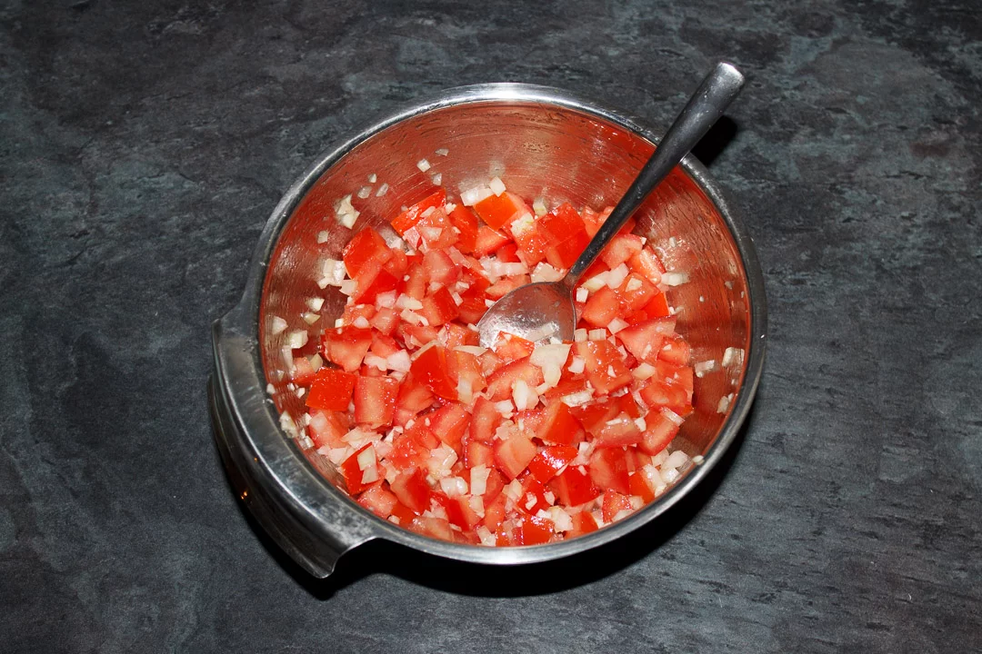 Diced desseded tomato, diced onion and garlic mixed together in a silver bowl