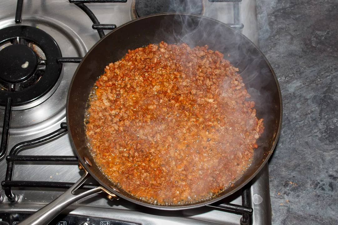 cooked soya mince in a frying pan with taco seasoning and water