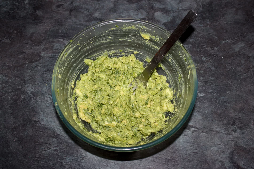 Guacamole in a glass bowl with a fork