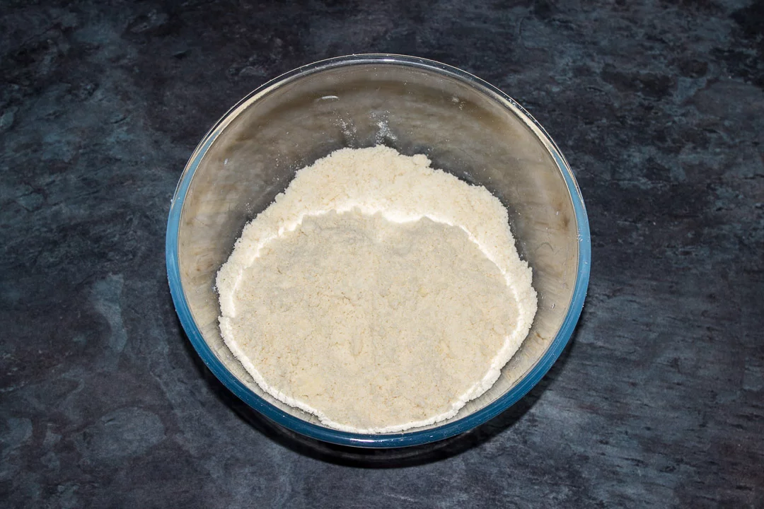 Butter, flour and salt in a glass bowl rubbed into crumbs