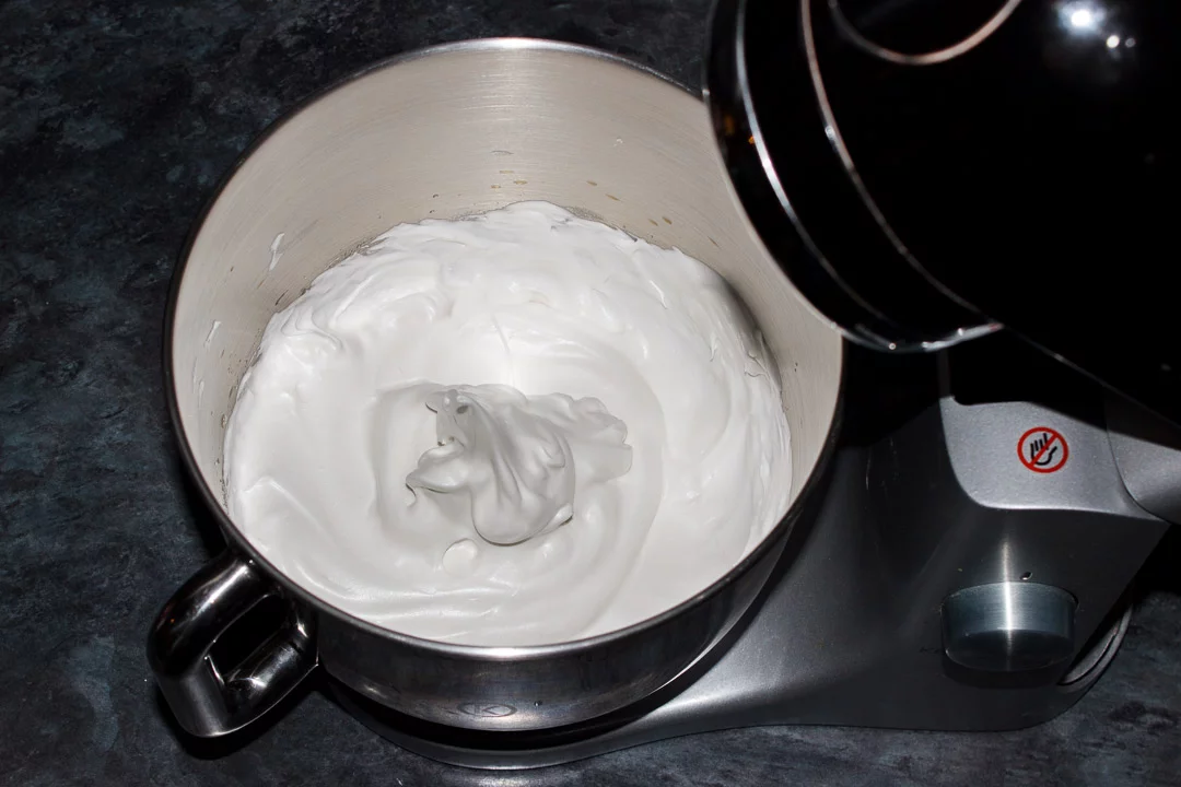Meringue in an electric stand mixer bowl at the stiff peaks stage