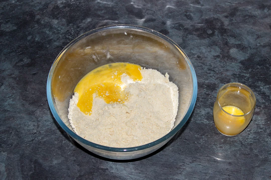 Butter, flour and salt in a glass bowl rubbed into crumbs with beaten egg