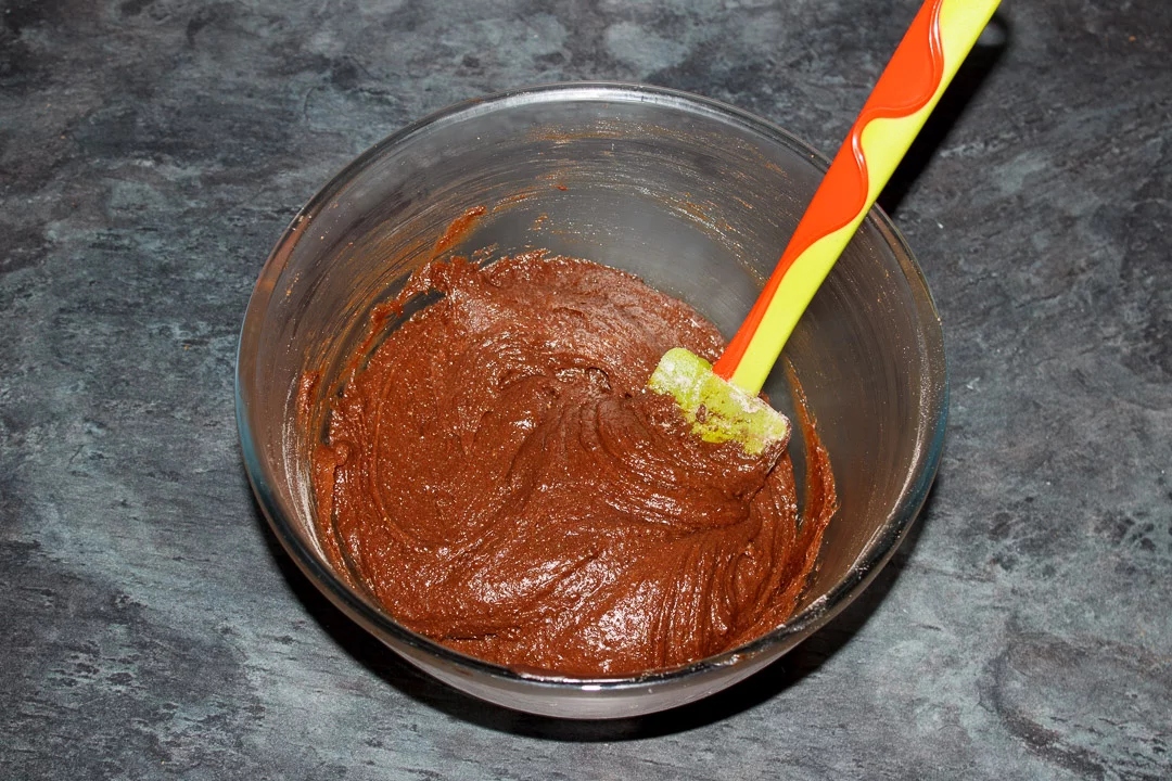 Millionaire brownie batter in a glass bowl with a green spatula