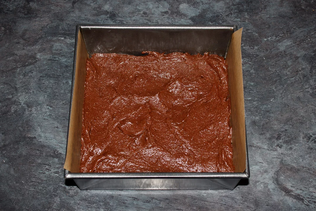 Millionaire brownie batter in a lined square baking tin