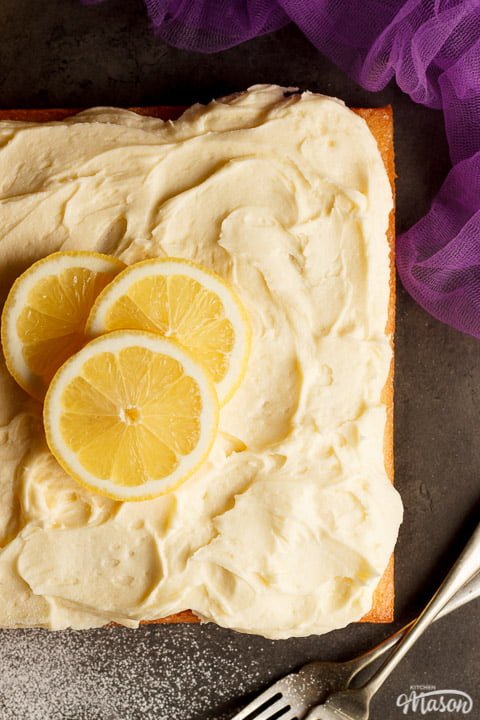 A lemon traybake cake on a worktop topped with lemon slices for decoration