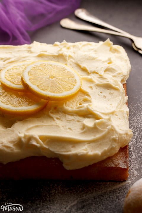 A lemon traybake cake on a worktop topped with lemon slices for decoration
