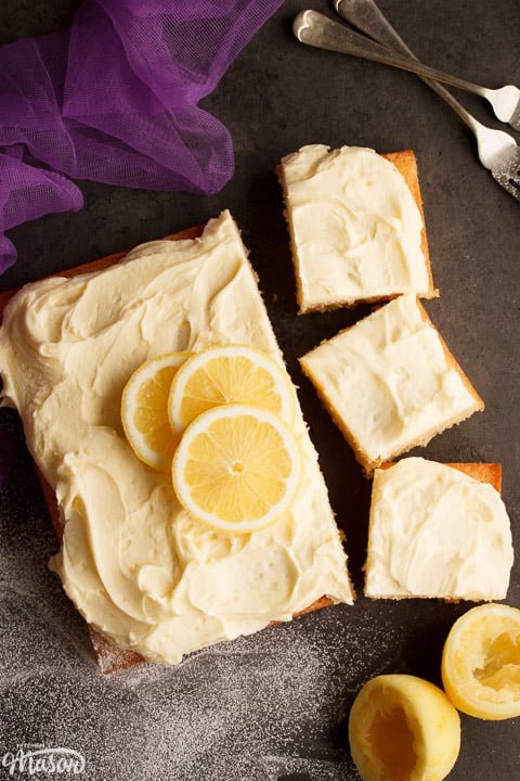 Lemon traybake part sliced on a worktop with slices of lemon on top