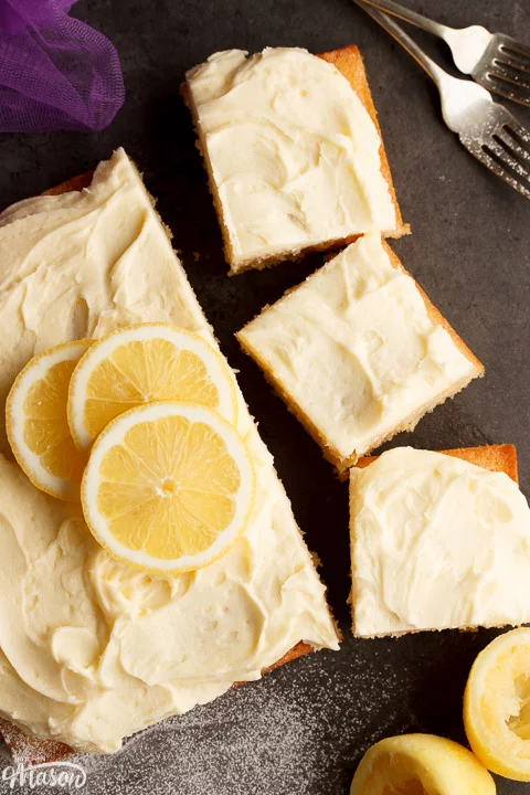 Lemon traybake part sliced on a worktop with slices of lemon on top