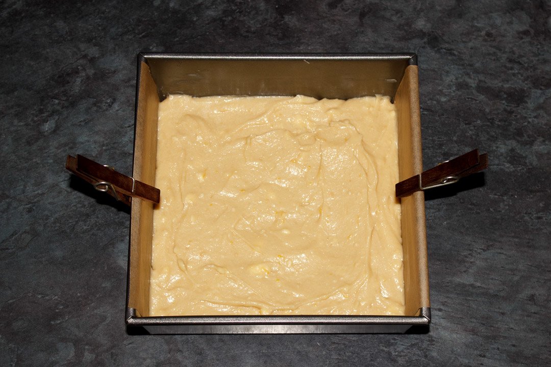 Lemon traybake cake batter smoothed out in a lined square baking tin