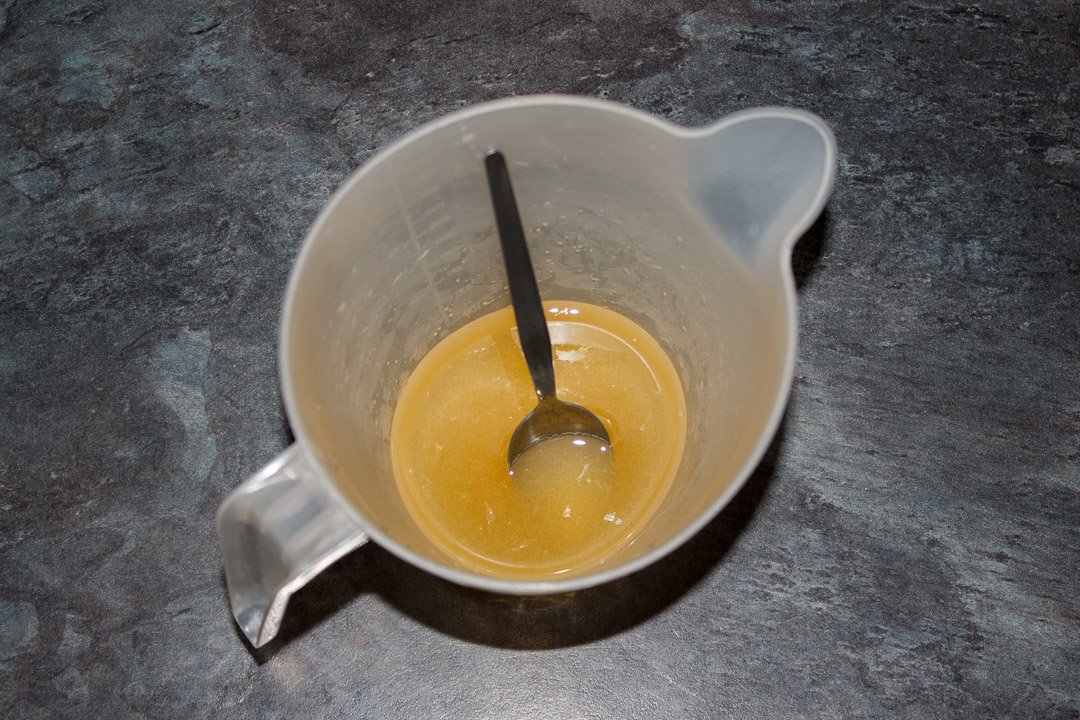 Sugar and lemon juice mixed together in a jug with a metal teaspoon