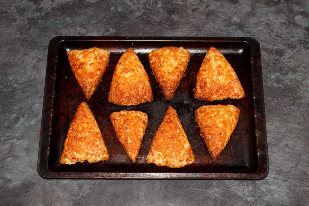 Freshly baked cheese scones on a baking tray.