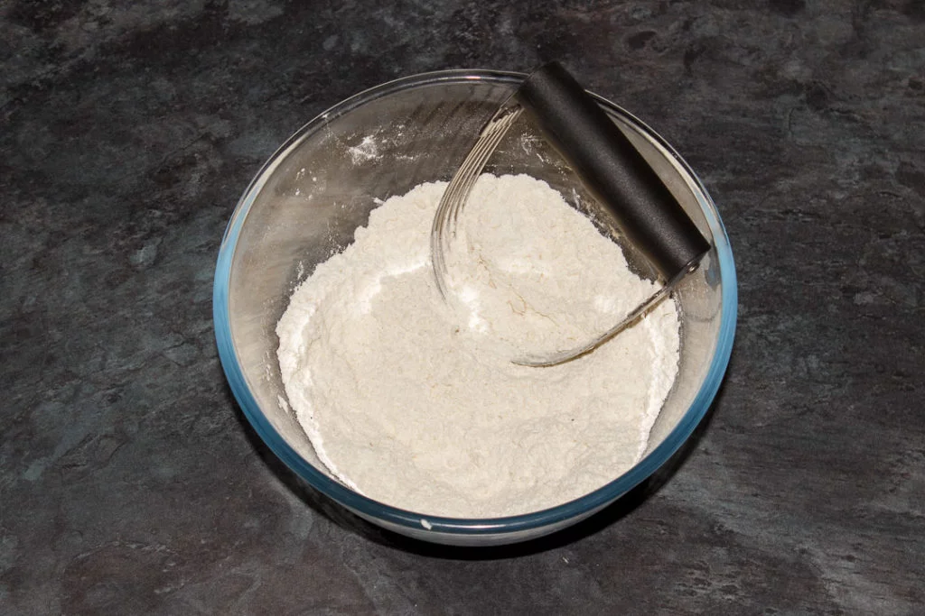 Flour, baking powder, seasonings and butter rubbed together in a bowl with a pastry blender.