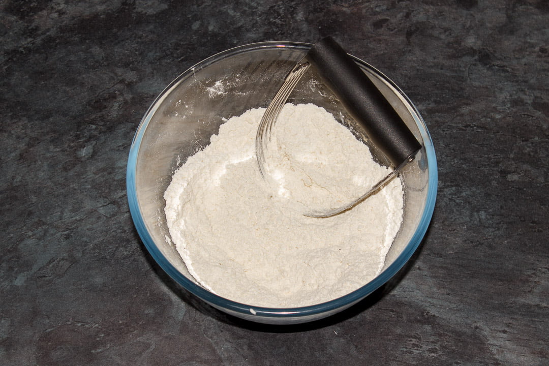 Flour, baking powder, seasoning and butter rubbed together in a bowl with a pastry whisk