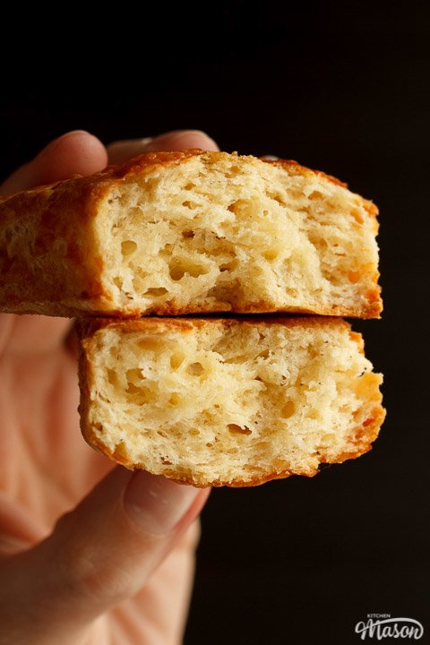 Two halves of a cheese scone being held so you can see the light flaky centre