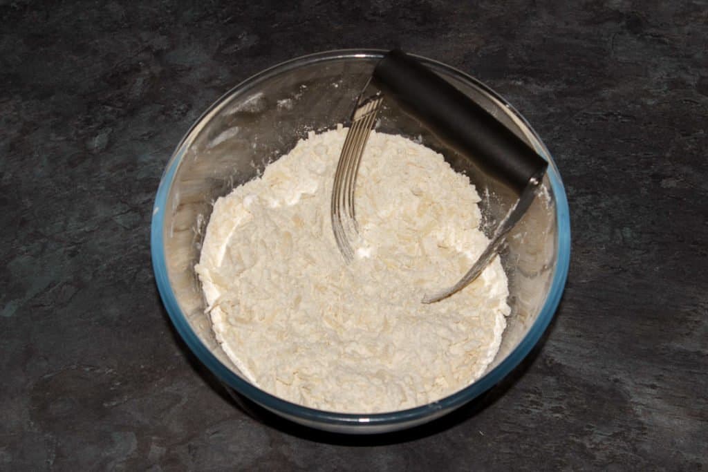 Cheese scones dry ingredients in a mixing bowl with a pastry blender.