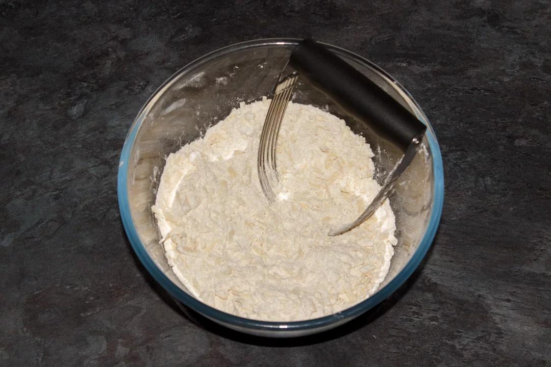 Cheese scones dry ingredients in a bowl with a pastry whisk