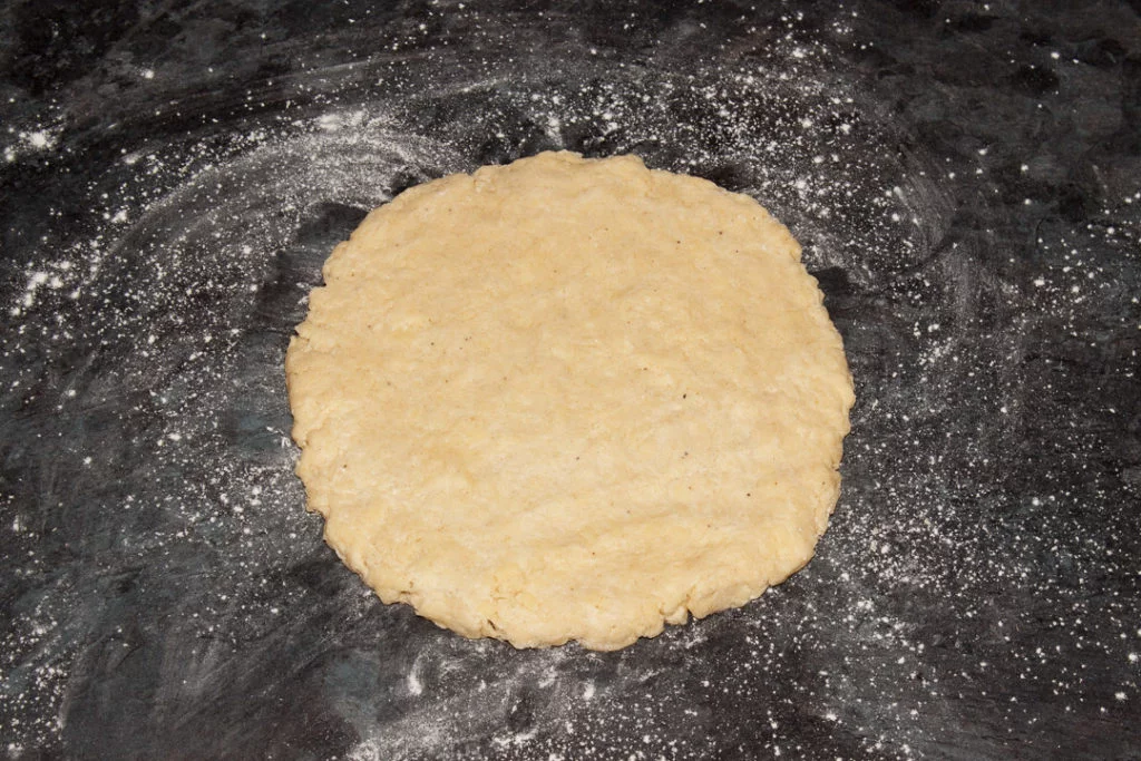 Cheese scones dough rolled out to a round, about 1" thick, on a lightly floured work surface.