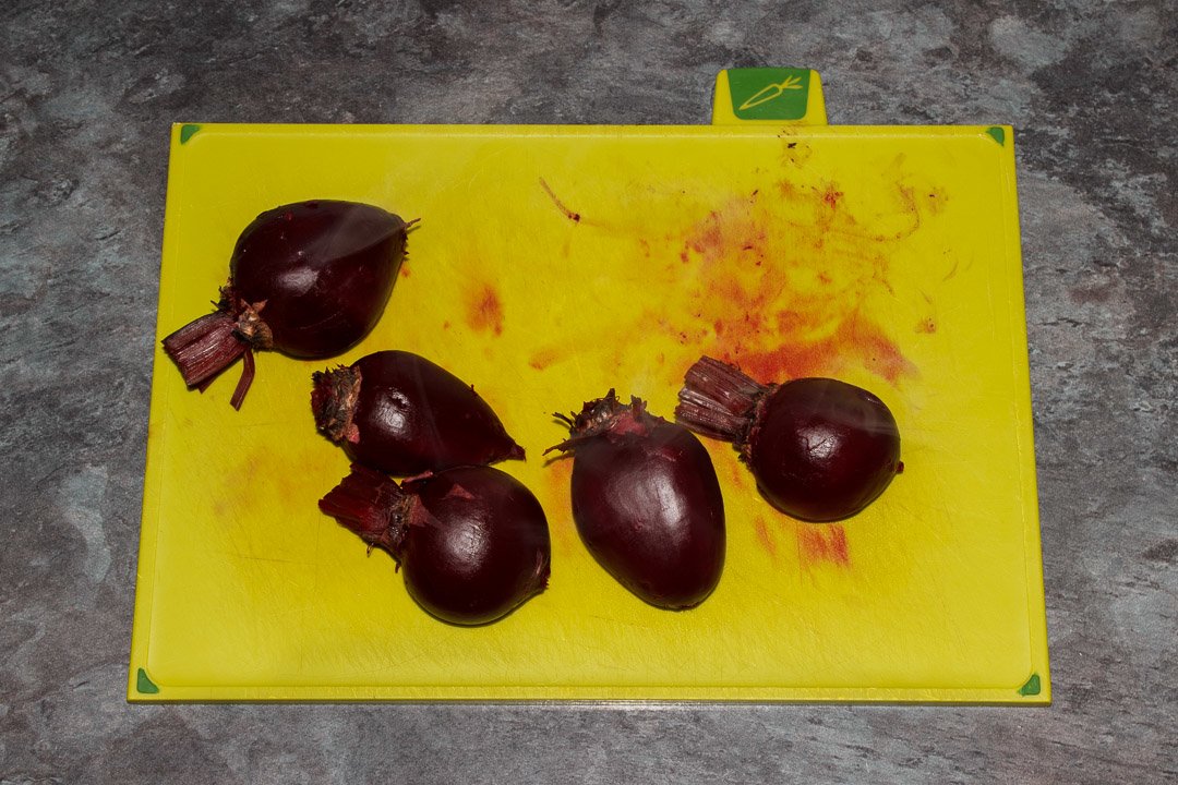 Whole beetroot with their skins peeled on a chopping board