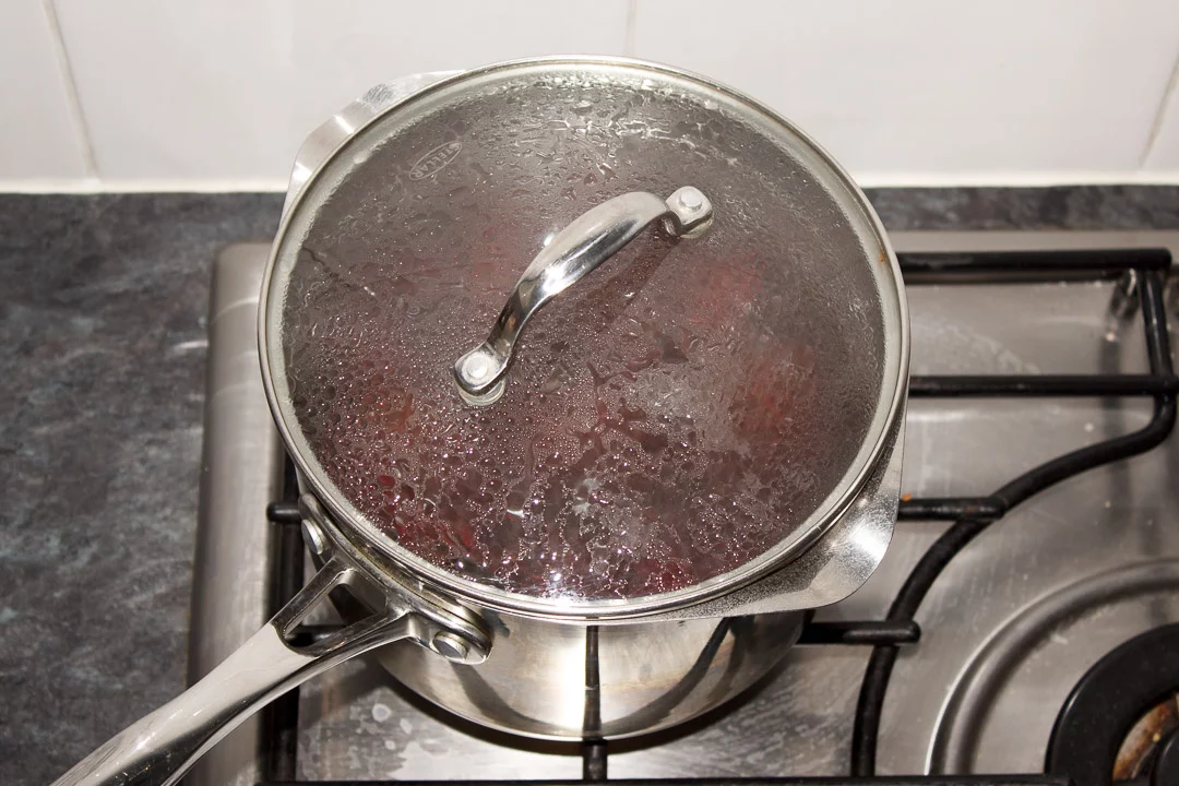 Whole beetroot simmering in a large saucepan with a lid on