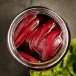 Pickled beetroot in a jar with a lettuce leaf next to it