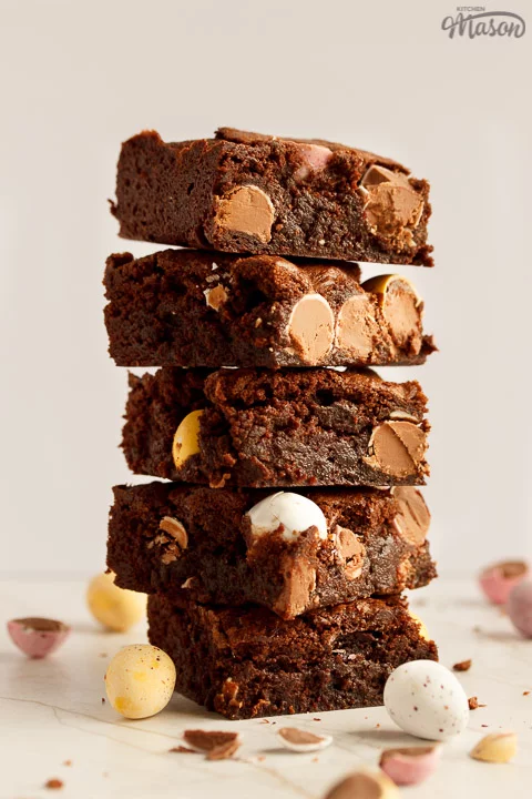 A stack of 5 Mini Egg brownies surrounded by broken Mini Eggs and Easter chicks