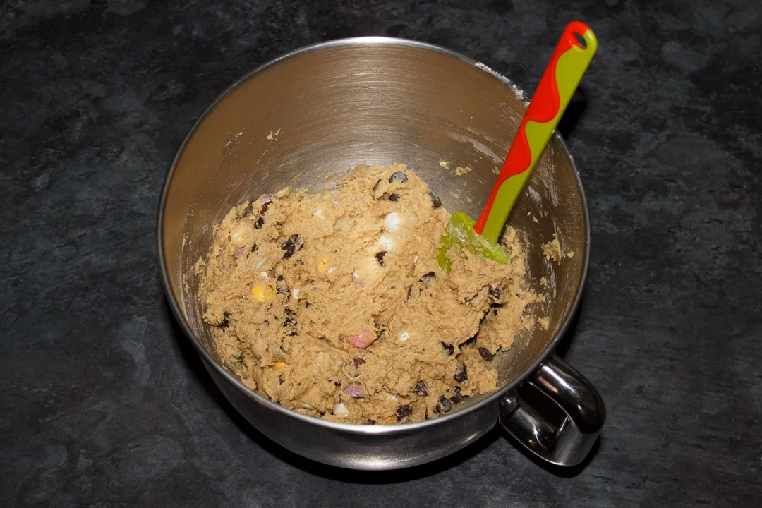 Mini Egg cookie dough in a large bowl with a green and orange rubber spatula