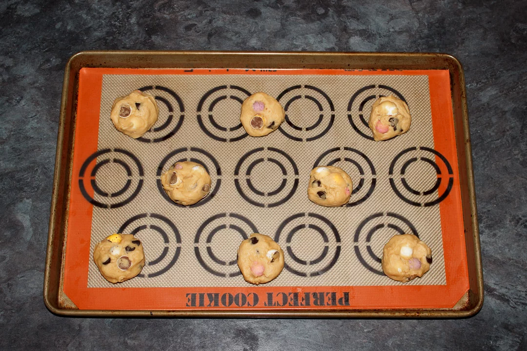 Mini Egg cookie dough balls on a lined baking tray