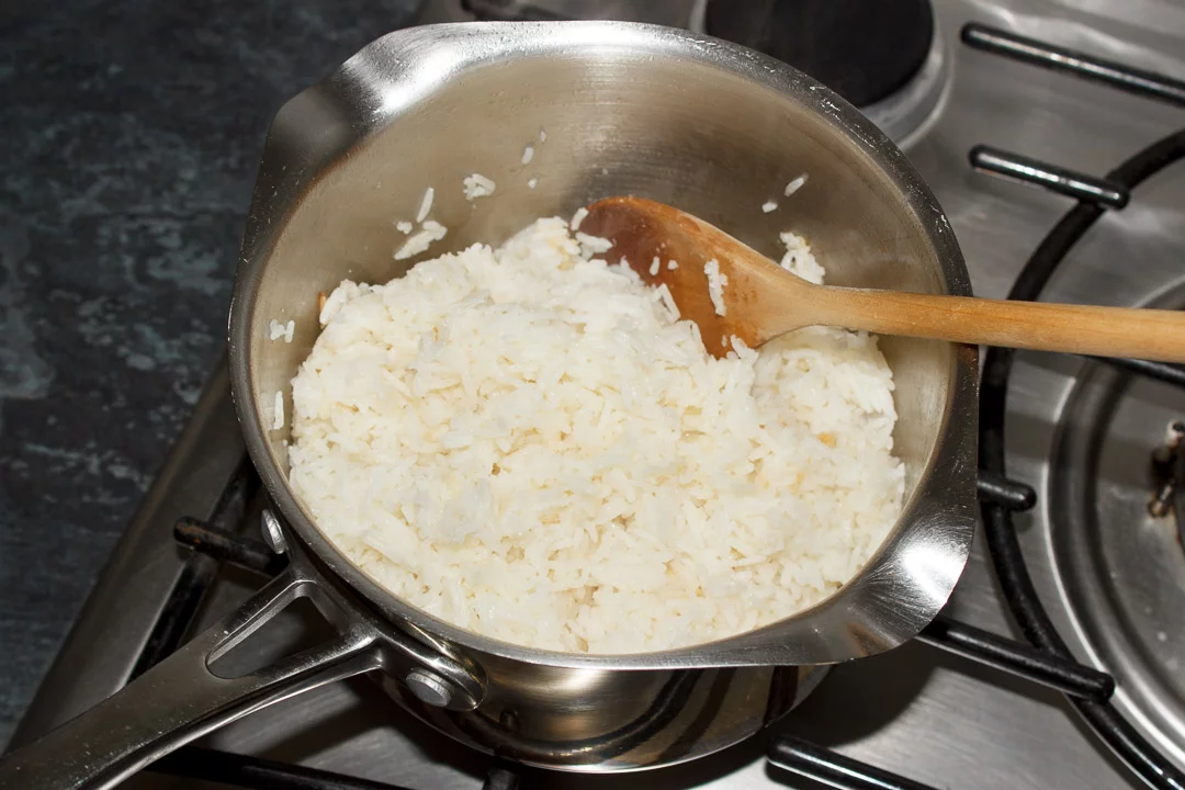 freshly cooked rice in a saucepan with a wooden spoon