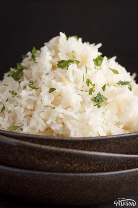 freshly cooked rice scattered with chopped coriander in the top bowl of a stack of 3