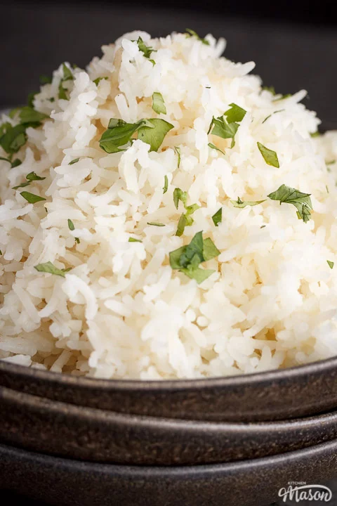 freshly cooked rice scattered with chopped coriander in the top bowl of a stack of 3