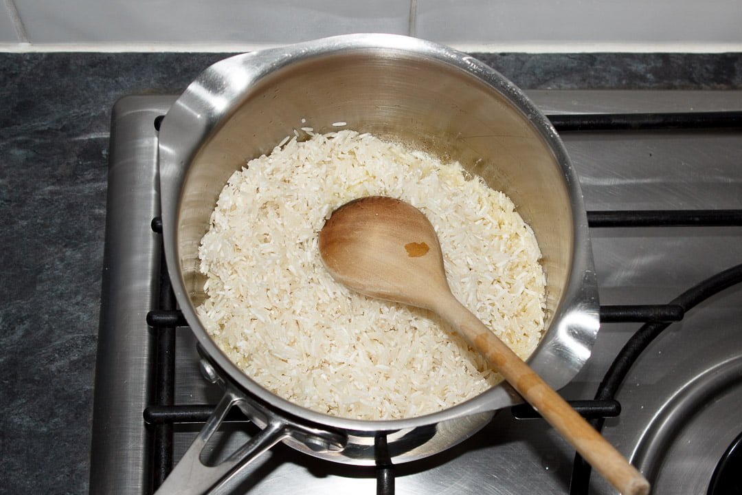 uncooked rice in a saucepan being fried in butter