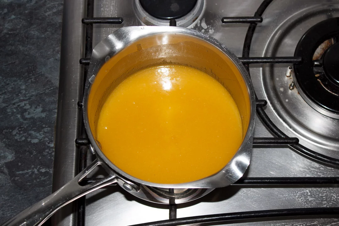 Melted butterscotch tart filling in a large saucepan on a stove top