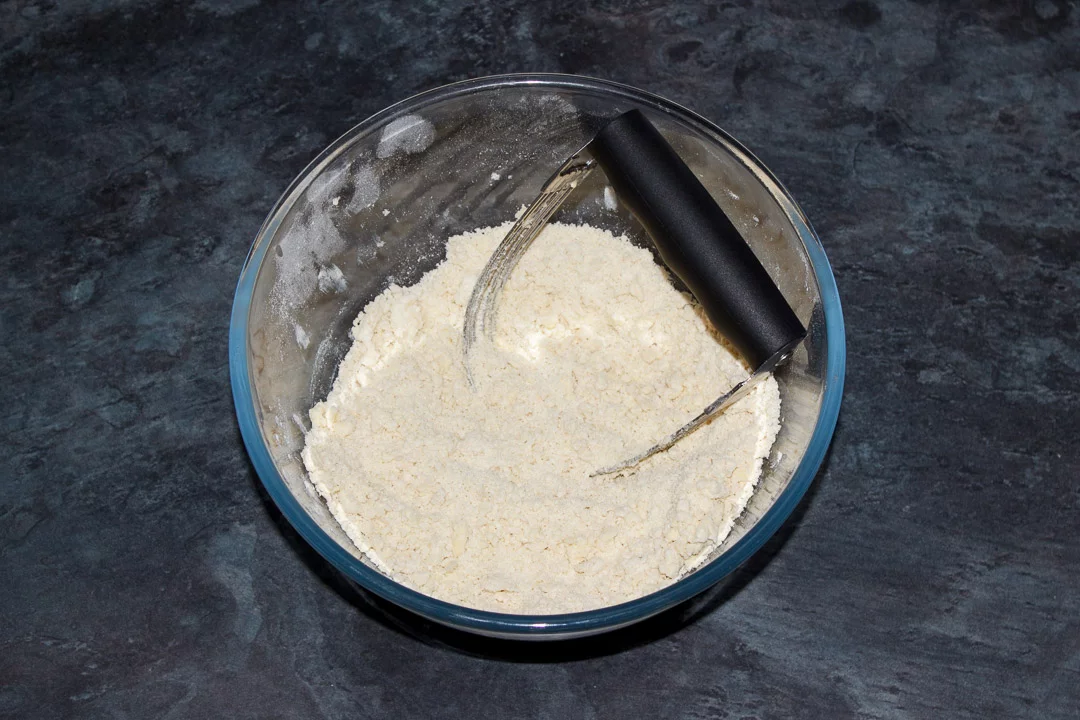 Butter, flour and salt blended to a crumble in a glass bowl with a pastry blender