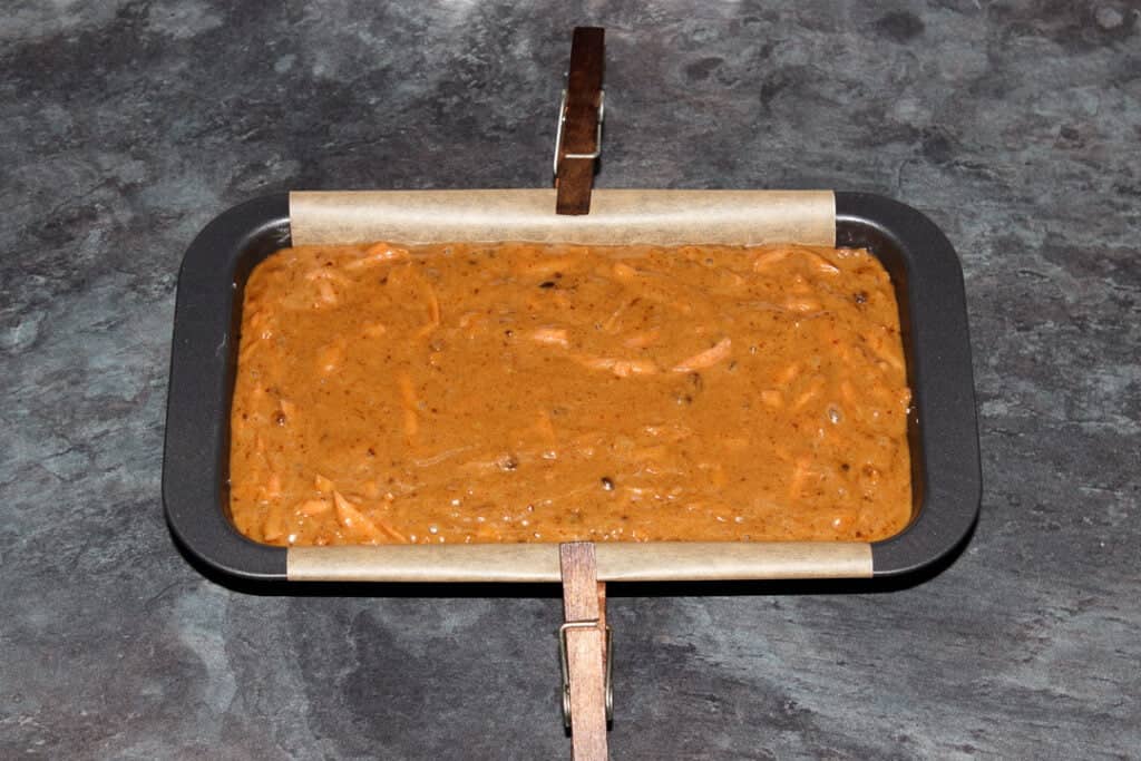 Carrot loaf cake batter in a lined loaf tin ready for the oven.