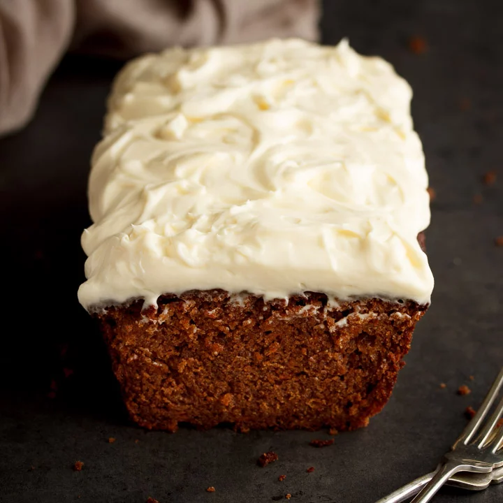 A carrot cake loaf on a kitchen worktop with two forks at the side.