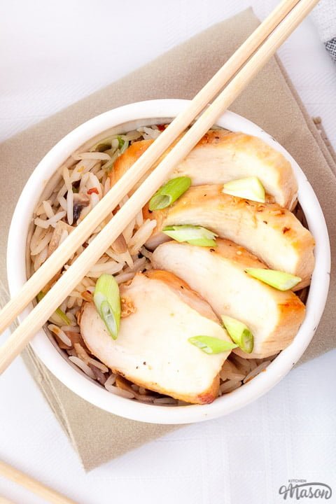 Chicken teriyaki in a small bowl with chop sticks balanced on top