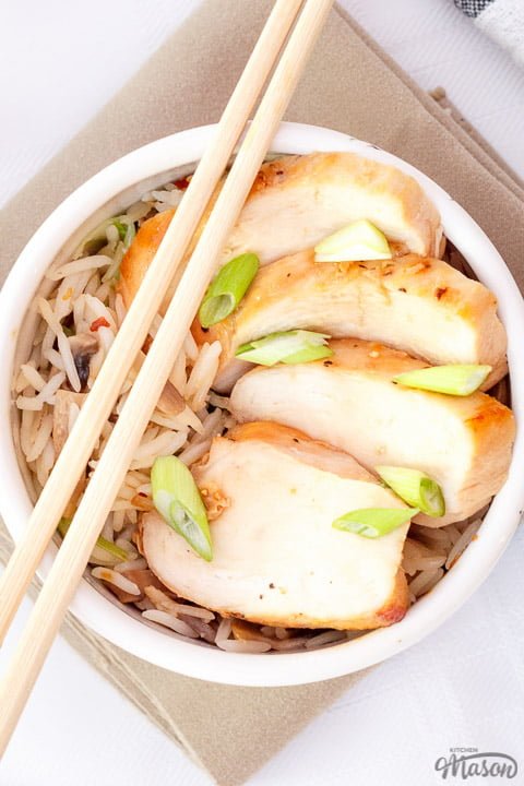 Chicken teriyaki in a small bowl with chop sticks balanced on top