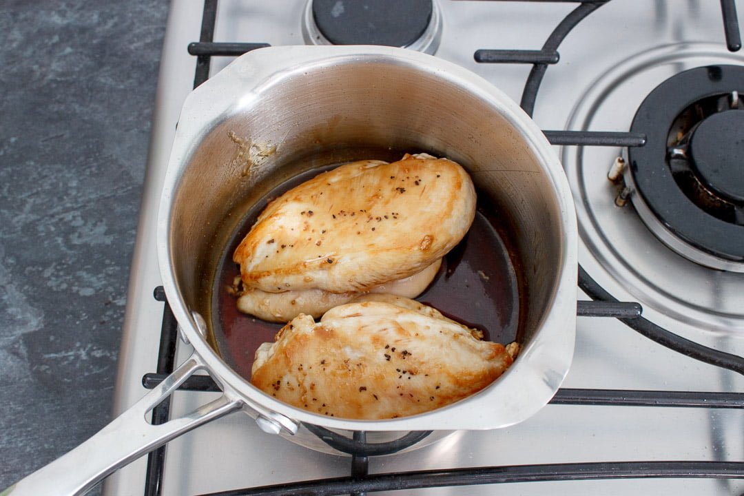 Soy sauce, mirin and caster sugar simmering in a small saucepan with 2 part cooked chicken breasts