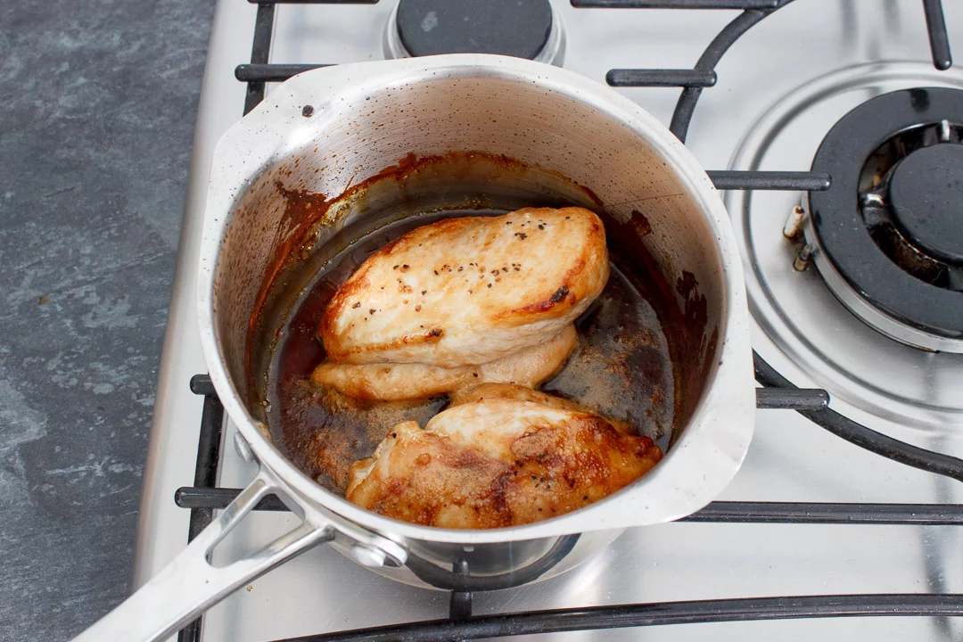 Soy sauce, mirin and caster sugar simmering in a small saucepan with 2 cooked chicken breasts