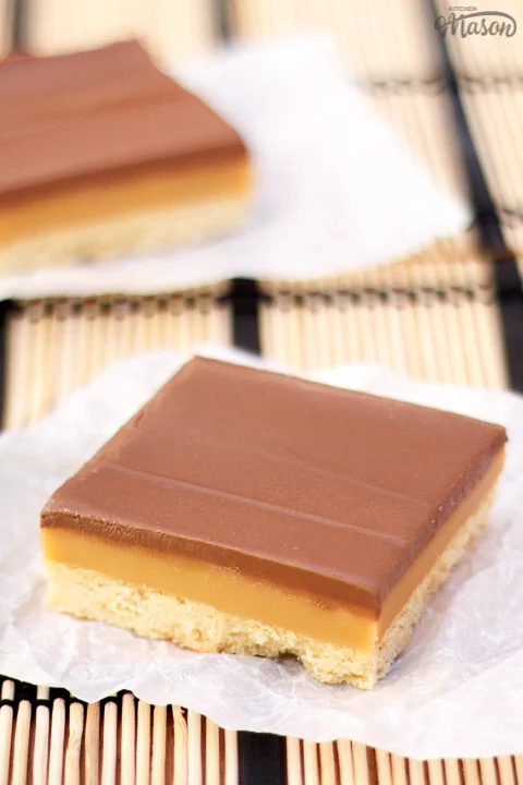 A bar of millionaire's shortbread on a scrunched up piece of white baking paper.